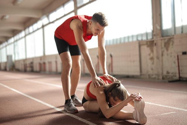 A girl doing stretches while her trainer helps her out