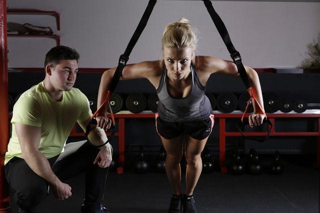 A girl doing exercises next to her trainer